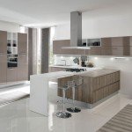 Terra di Aran in versione con penisola, attrezzata con un ulteriore piano per la preparazione dei cibi e per consumare colazioni o pasti veloci. La composizione gioca con i pieni e i vuoti grazie a una ampia componibiltà e al contrasto materico del polimerico o del laminato e delle finiture essenza.