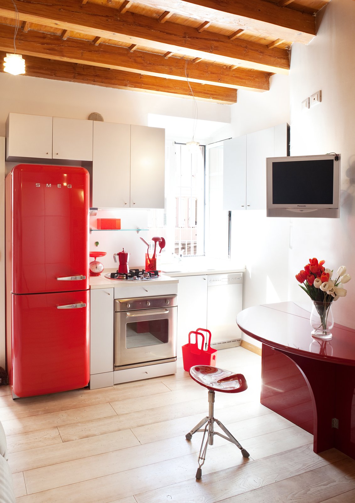 cucina piccola bianca sotto la finestra, con frigo rosso e pensili salvaspazio cucina piccola bianca sotto la finestra, con frigo rosso e pensili salvaspazio