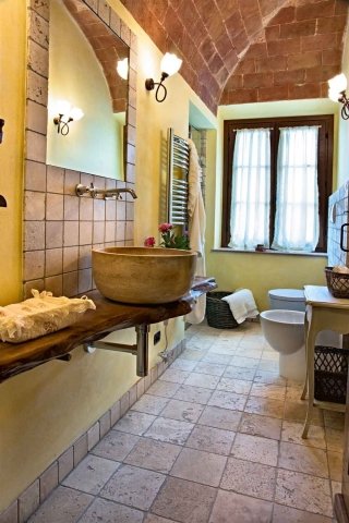 Il rivestimento da parete di Cristiani è in travertino noce chiaro leggermente anticato. Questo effetto si ottiene facendo ruzzolare le piastrelle in una betoniera con sassi e sabbia. Formato 10 x 10 cm, spessore 10 mm. Prezzo al m² 25 euro. www.cristiani.it