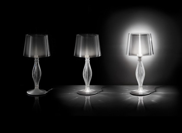 Liza di Slamp (design Elisa Giovannoni) si ispira alle classiche abat-jour di cristallo ma è realizzata con il più contemporaneo Lentiflex®, materiale plastico dalla superficie sfaccettata che cambia aspetto e colore a seconda del punto di osservazione. I tagli verticali di cappello e stelo proiettano su pareti e soffitto giochi di luci e ombre, mentre un LED di cortesia alloggiato nella base può essere acceso anche indipendentemente come discreta fonte luminosa di cortesia. Ø base 35 cm, H 70 cm. www.slamp.it Liza di Slamp (design Elisa Giovannoni) si ispira alle classiche abat-jour di cristallo ma è realizzata con il più contemporaneo Lentiflex®, materiale plastico dalla superficie sfaccettata che cambia aspetto e colore a seconda del punto di osservazione. I tagli verticali di cappello e stelo proiettano su pareti e soffitto giochi di luci e ombre, mentre un LED di cortesia alloggiato nella base può essere acceso anche indipendentemente come discreta fonte luminosa di cortesia. Ø base 35 cm, H 70 cm. www.slamp.it