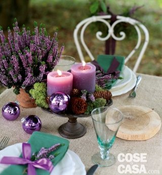 decorazione natalizia di erica viola, conifere e pigne con candele viola