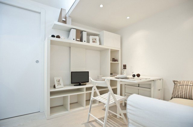 ) La funzionalità guida tutte le scelte di arredo del monolocale, dotato di mobili flessibili nell’utilizzo e trasformisti: libreria che serve anche da parete attrezzata per televisore e/o apparecchi tecnologici per l’intrattenimento, tavolo-consolle a ribalta, contenitori sia a giorno sia chiusi, sedia pieghevole salva spazio. Tutto assolutamente total white per esaltarne il tratto minimalista e contemporaneo. Anche l’illuminazione è progettata in tal senso, con apparecchi integrati nelle strutture architettoniche che rendono protagonista solo la luce ) La funzionalità guida tutte le scelte di arredo del monolocale, dotato di mobili flessibili nell’utilizzo e trasformisti: libreria che serve anche da parete attrezzata per televisore e/o apparecchi tecnologici per l’intrattenimento, tavolo-consolle a ribalta, contenitori sia a giorno sia chiusi, sedia pieghevole salva spazio. Tutto assolutamente total white per esaltarne il tratto minimalista e contemporaneo. Anche l’illuminazione è progettata in tal senso, con apparecchi integrati nelle strutture architettoniche che rendono protagonista solo la luce