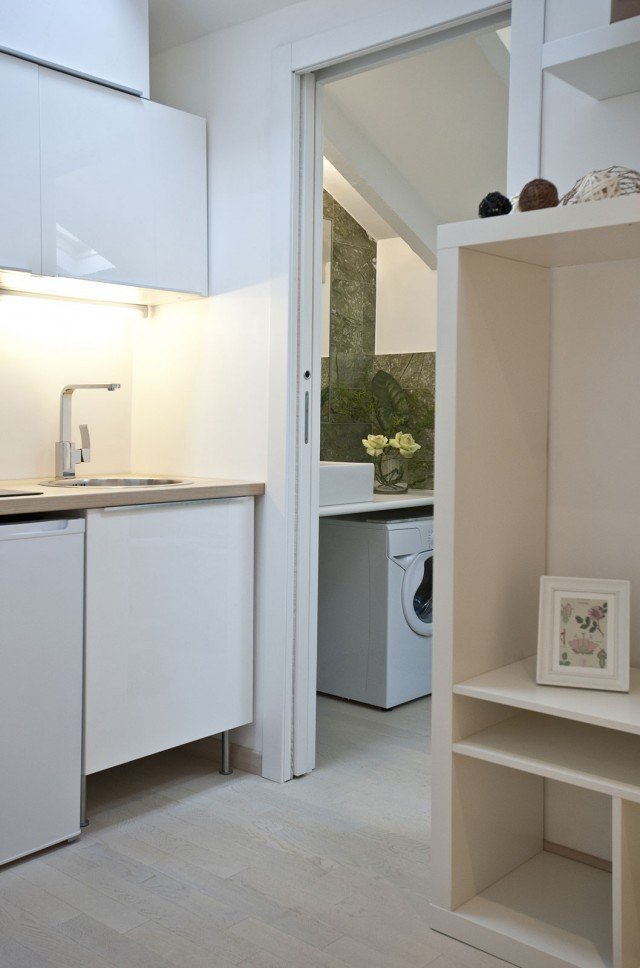 Contiguo all’angolo cucina è l’antibagno, separato dal resto della mansarda da una porta scorrevole bianca che non interrompe la prospettiva visiva e posizionato, così come il bagno, nella porzione di sottotetto più bassa. Grazie a questo piccolo ambiente di servizio, che funziona anche da mini-lavanderia, quando viene lasciata aperta la porta non si ha la percezione della presenza di un bagno, dato che lavabo e sanitari risultano tutti nascosti. Contiguo all’angolo cucina è l’antibagno, separato dal resto della mansarda da una porta scorrevole bianca che non interrompe la prospettiva visiva e posizionato, così come il bagno, nella porzione di sottotetto più bassa. Grazie a questo piccolo ambiente di servizio, che funziona anche da mini-lavanderia, quando viene lasciata aperta la porta non si ha la percezione della presenza di un bagno, dato che lavabo e sanitari risultano tutti nascosti.