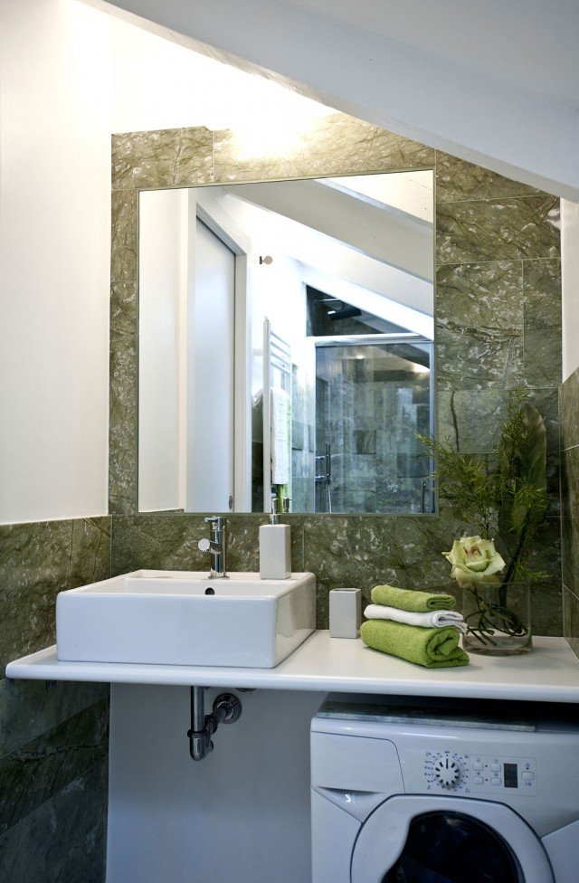 Tratto minimalista per l’antibagno: semplice ripiano laccato bianco con lavabo a vaschetta ad appoggio e lavatrice a vista sottopiano, specchio applicato direttamente a parete a filo muro, senza cornice o sostegno. Unica concessione al decoro il rivestimento alle pareti, realizzato con lastre di marmo verde Ming importate dall’Oriente e tagliate con spessori e dimensioni differenti. Tratto minimalista per l’antibagno: semplice ripiano laccato bianco con lavabo a vaschetta ad appoggio e lavatrice a vista sottopiano, specchio applicato direttamente a parete a filo muro, senza cornice o sostegno. Unica concessione al decoro il rivestimento alle pareti, realizzato con lastre di marmo verde Ming importate dall’Oriente e tagliate con spessori e dimensioni differenti.
