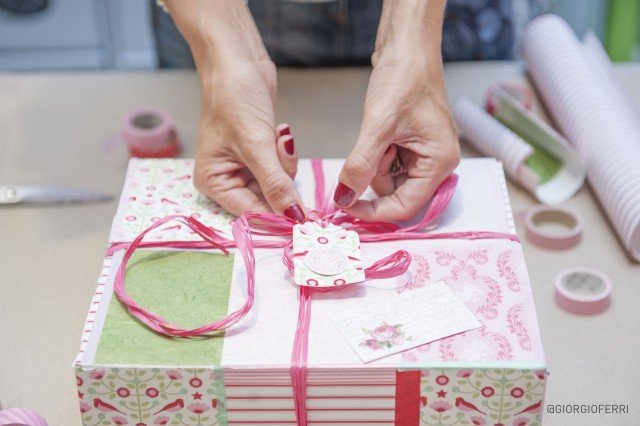 Dopo aver inserito il regalo si può chiudere la scatola con un nastro per pacchi (oppure un filo di lana, spago, raso, rafia, ecc…) ma prima occorre ritagliare con le forbici un’etichetta rettangolare da un cartoncino colorato, perforarla sul lato più corto e poi va passato il nastro di chiusura all’interno del foro. Un bel nodo e il gioco è fatto! Dopo aver inserito il regalo si può chiudere la scatola con un nastro per pacchi (oppure un filo di lana, spago, raso, rafia, ecc…) ma prima occorre ritagliare con le forbici un’etichetta rettangolare da un cartoncino colorato, perforarla sul lato più corto e poi va passato il nastro di chiusura all’interno del foro. Un bel nodo e il gioco è fatto!