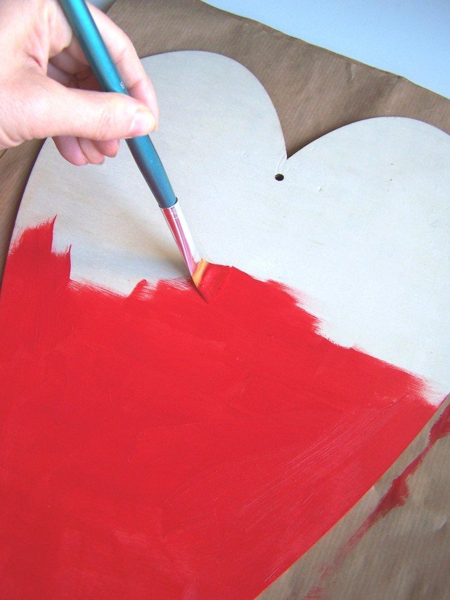 Dipingere una sagoma di compensato della forma desiderata, in questo caso un cuore, con due mani di colore acrilico rosso, senza dimenticare il bordo esterno (Foto 1). Dipingere una sagoma di compensato della forma desiderata, in questo caso un cuore, con due mani di colore acrilico rosso, senza dimenticare il bordo esterno (Foto 1).