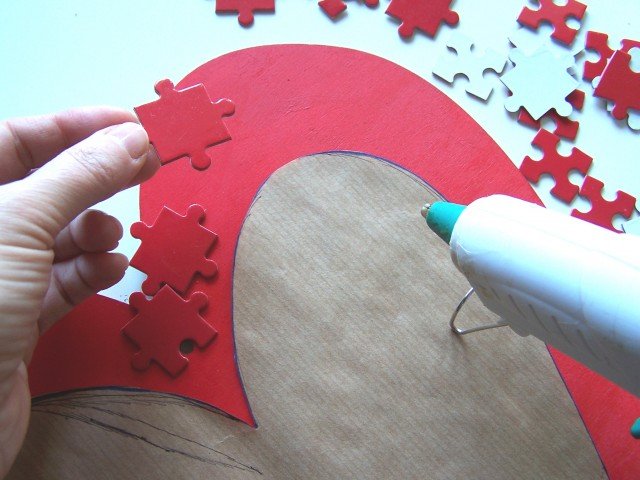 Incollare i pezzi del puzzle uno ad uno con al colla a caldo, facendoli fuoriuscire dal bordo e sovrapponendoli (Foto 6). Non preoccupatevi dei fili di colla perché, una volta finito di incollare i pezzi, si potranno tirare via senza problemi. Incollare i pezzi del puzzle uno ad uno con al colla a caldo, facendoli fuoriuscire dal bordo e sovrapponendoli (Foto 6). Non preoccupatevi dei fili di colla perché, una volta finito di incollare i pezzi, si potranno tirare via senza problemi.