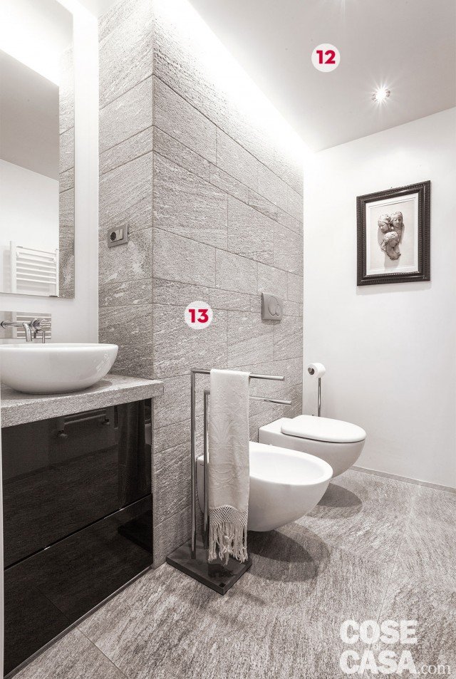 12. Controsoffitto luminoso
Nel bagno un ribassamente centrale realizzato con un pannello in cartongesso permette di alloggiare due fonti luminose diverse: faretti a incasso al centro e una striscia a led lungo il bordo, nell'intercapedine tra plafone e controsoffitto.
13. Spessori diversi a parete
Alla porzione di muro portante di elevato spessore che divide il bagno dalla cucina sono fissati i sanitari sospesi. Di fianco, il piano del lavabo e il bacino da appoggio sono invece inseriti in una rientranza che in precedenza era occupata da una canna fumaria. 12. Controsoffitto luminoso
Nel bagno un ribassamente centrale realizzato con un pannello in cartongesso permette di alloggiare due fonti luminose diverse: faretti a incasso al centro e una striscia a led lungo il bordo, nell'intercapedine tra plafone e controsoffitto.
13. Spessori diversi a parete
Alla porzione di muro portante di elevato spessore che divide il bagno dalla cucina sono fissati i sanitari sospesi. Di fianco, il piano del lavabo e il bacino da appoggio sono invece inseriti in una rientranza che in precedenza era occupata da una canna fumaria.