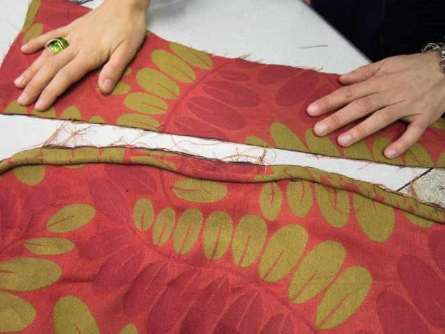 Cucire il cordoncino sulla stoffa precedentemente tagliata; quindi giuntare a questi una fascia alta quanto l'altezza della seduta, più 3/4 cm da ripiegare poi sotto la base. Cucire i due pezzi dal rovescio. Cucire il cordoncino sulla stoffa precedentemente tagliata; quindi giuntare a questi una fascia alta quanto l'altezza della seduta, più 3/4 cm da ripiegare poi sotto la base. Cucire i due pezzi dal rovescio.