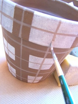 Dipingete tutto il vaso con la spugna, procedendo come sopra. Fate asciugare bene e rimuovete il nastro carta. Dopo aver creato un colore intermedio a contrasto (es. marrone più chiaro o grigio), con un pennello a punta n. 2, disegnate le righine perpendicolari Dipingete tutto il vaso con la spugna, procedendo come sopra. Fate asciugare bene e rimuovete il nastro carta. Dopo aver creato un colore intermedio a contrasto (es. marrone più chiaro o grigio), con un pennello a punta n. 2, disegnate le righine perpendicolari