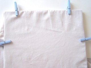 Prendete il cartone e fissatelo sotto la stoffa con l’aiuto delle mollette.