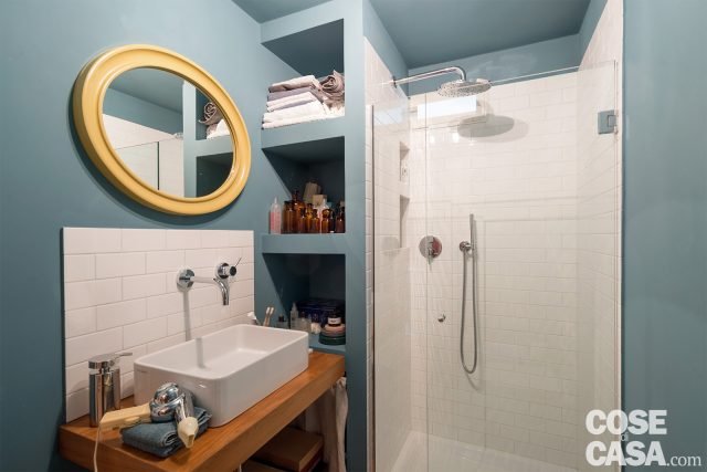 L’unico bagno, al piano inferiore, è suddiviso in due vani distinti. Nell’antibagno lavabo e box doccia sono disposti a 90°, divisi da un elemento strutturale che occupa la zona d’angolo. Le due funzioni sono identificate dalla piastrellatura in bianco, contrapposta all’azzurro carta da zucchero delle pareti. L’unico bagno, al piano inferiore, è suddiviso in due vani distinti. Nell’antibagno lavabo e box doccia sono disposti a 90°, divisi da un elemento strutturale che occupa la zona d’angolo. Le due funzioni sono identificate dalla piastrellatura in bianco, contrapposta all’azzurro carta da zucchero delle pareti.