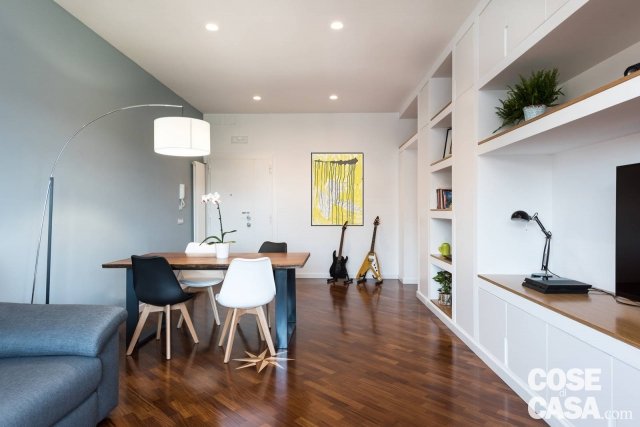 Il soggiorno, a cui si accede dalla porta di ingresso della casa (senza alcuna mediazione spaziale per non rubare spazio utile), organizza senza soluzione di continuità un’area per il pranzo degli ospiti o il lavoro e la zona conversazione e relax. Il calore del parquet preesistente è volutamente esaltato dalla scelta total white di pareti e soffitto, ad eccezione del grigio di un’unica parete. Il tavolo su disegno, con struttura di ferro e piano orizzontale di rovere di alto spessore, è abbinato a sedie Dalani con scocca di plastica bianca e nera e alla scenografica lampada da terra Torino di Maison du Monde. E protegge l’angolo del divano Poltronesofà rivestito di tessuto grigio di ispirazione sartoriale senza interrompere la vista e il passaggio della luce naturale. Il soggiorno, a cui si accede dalla porta di ingresso della casa (senza alcuna mediazione spaziale per non rubare spazio utile), organizza senza soluzione di continuità un’area per il pranzo degli ospiti o il lavoro e la zona conversazione e relax. Il calore del parquet preesistente è volutamente esaltato dalla scelta total white di pareti e soffitto, ad eccezione del grigio di un’unica parete. Il tavolo su disegno, con struttura di ferro e piano orizzontale di rovere di alto spessore, è abbinato a sedie Dalani con scocca di plastica bianca e nera e alla scenografica lampada da terra Torino di Maison du Monde. E protegge l’angolo del divano Poltronesofà rivestito di tessuto grigio di ispirazione sartoriale senza interrompere la vista e il passaggio della luce naturale.