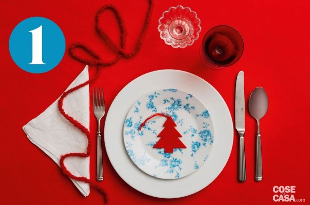 Con una sagomina a forma di alberello, il segnaposto ritagliato nel pannolenci o nel feltro caratterizza la tavola delle feste, insieme al cordoncino di lana (lungo e un po’ spesso) fatto cadere come un ghirigoro. Insolito l’abbinamento del piatto a fiorellini azzurri con il rosso lacca della tovaglia. Con una sagomina a forma di alberello, il segnaposto ritagliato nel pannolenci o nel feltro caratterizza la tavola delle feste, insieme al cordoncino di lana (lungo e un po’ spesso) fatto cadere come un ghirigoro. Insolito l’abbinamento del piatto a fiorellini azzurri con il rosso lacca della tovaglia.