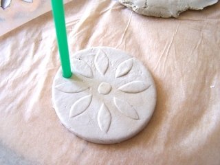 Con una cannuccia, fate il foro su ogni disco. Con una cannuccia, fate il foro su ogni disco.
