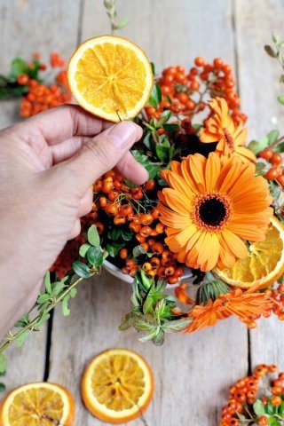 6. Disponete sull’asse arancione le tazze floreali, alternandole alle arance con tealight e alle candele di varie misure.