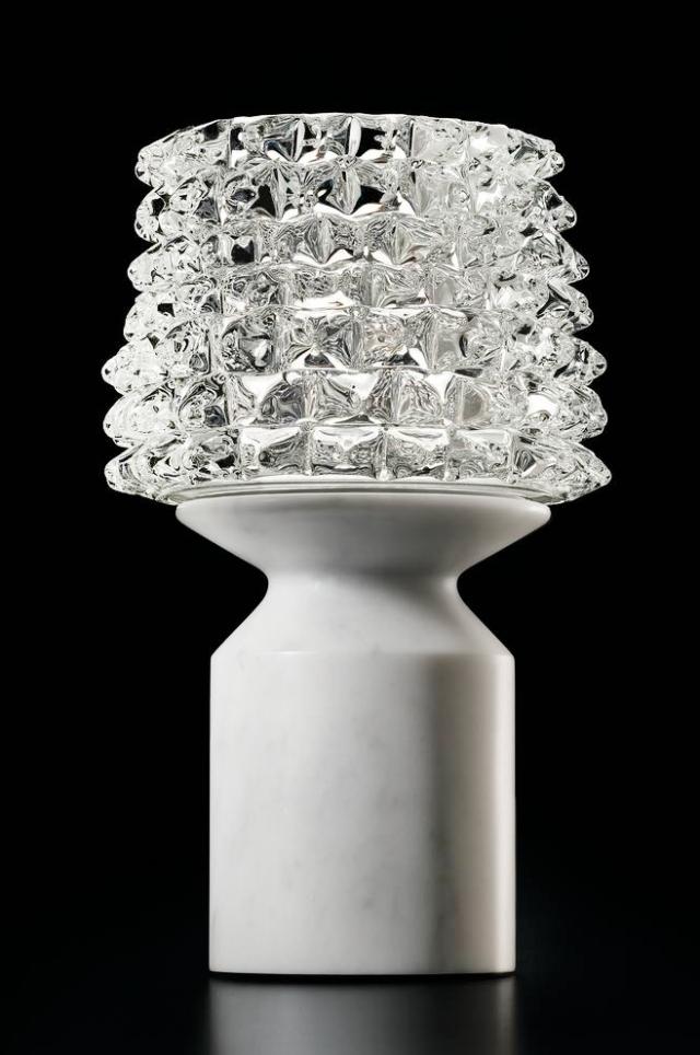 Camparino di Barovier & Toso, è la lampada da tavolo ispirata agli Anni Trenta: è realizzata con la tecnica muranese del rostrato, una complessa lavorazione artigianale del vetro inventata nel 1938, che dà vita ad una serie di punte sul paralume; la base è in marmo pregiato. É alimentata da una batteria al litio ricaricabile che permette di trasportare la lampada dove si desidera; inoltre la tecnologia contactless consente l'accensione, lo spegimento e la regolazione dell'intensità luminosa. www.barovier.com Camparino di Barovier & Toso, è la lampada da tavolo ispirata agli Anni Trenta: è realizzata con la tecnica muranese del rostrato, una complessa lavorazione artigianale del vetro inventata nel 1938, che dà vita ad una serie di punte sul paralume; la base è in marmo pregiato. É alimentata da una batteria al litio ricaricabile che permette di trasportare la lampada dove si desidera; inoltre la tecnologia contactless consente l'accensione, lo spegimento e la regolazione dell'intensità luminosa. www.barovier.com