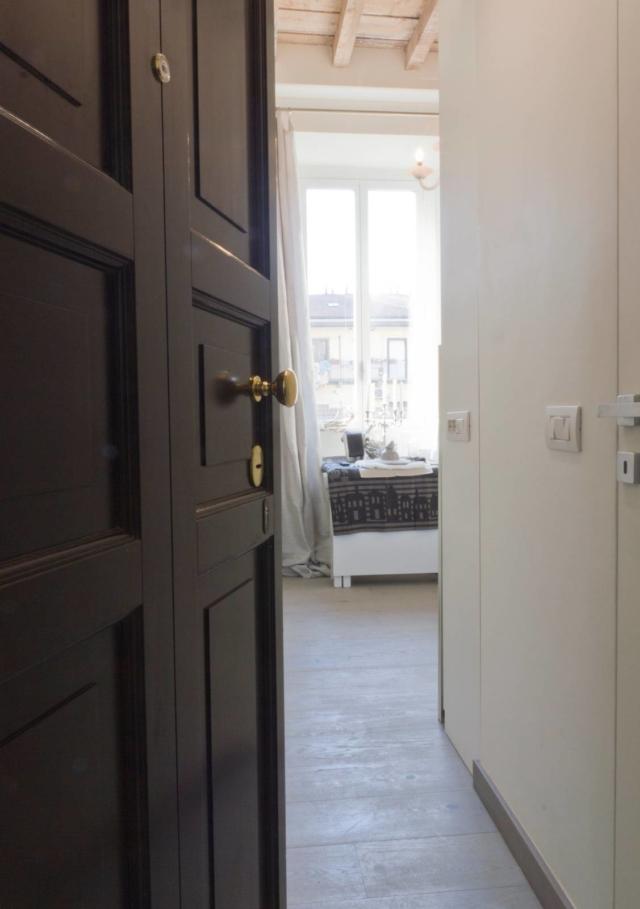 La porta d’ingresso blindata – rivestita esternamente con un pannello a riquadri che richiama lo stile dei serramenti “vecchia Milano” e dotata di accessori d’ottone – si apre direttamente sullo spazio interno. Il bianco dell’interno comunica un’idea di contemporaneità e di sobrietà diffusa, aumentando la luminosità naturale della grande finestra, mentre al soffitto e al parquet prefinito nei toni del grigio tortora è affidato il compito di dare calore all’insieme. La porta d’ingresso blindata – rivestita esternamente con un pannello a riquadri che richiama lo stile dei serramenti “vecchia Milano” e dotata di accessori d’ottone – si apre direttamente sullo spazio interno. Il bianco dell’interno comunica un’idea di contemporaneità e di sobrietà diffusa, aumentando la luminosità naturale della grande finestra, mentre al soffitto e al parquet prefinito nei toni del grigio tortora è affidato il compito di dare calore all’insieme.
