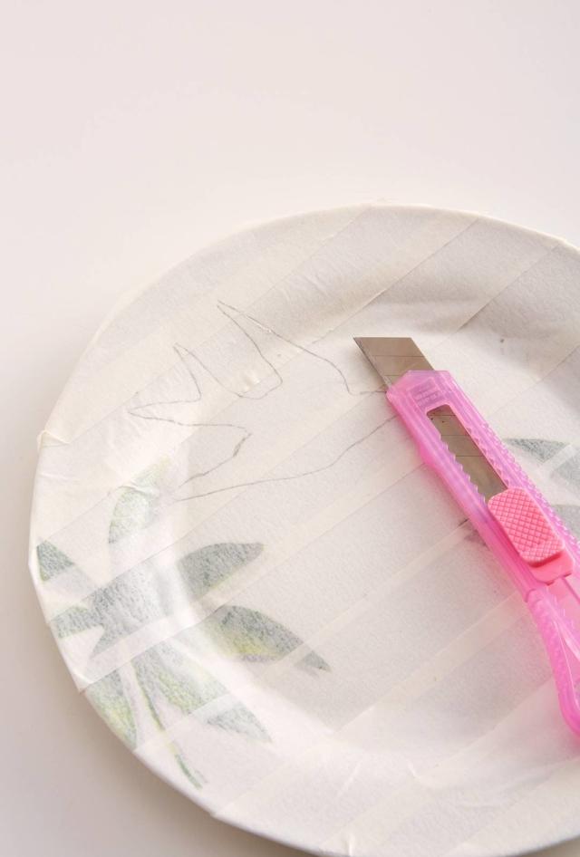 Con attenzione, incidete i contorni del disegno a matita con il cutter. Agite con una pressione costante facendo attenzione a non segnare il piatto. Eliminate il nastro di carta in eccesso, lasciando solo la parte con la sagoma disegnata. Con attenzione, incidete i contorni del disegno a matita con il cutter. Agite con una pressione costante facendo attenzione a non segnare il piatto. Eliminate il nastro di carta in eccesso, lasciando solo la parte con la sagoma disegnata.