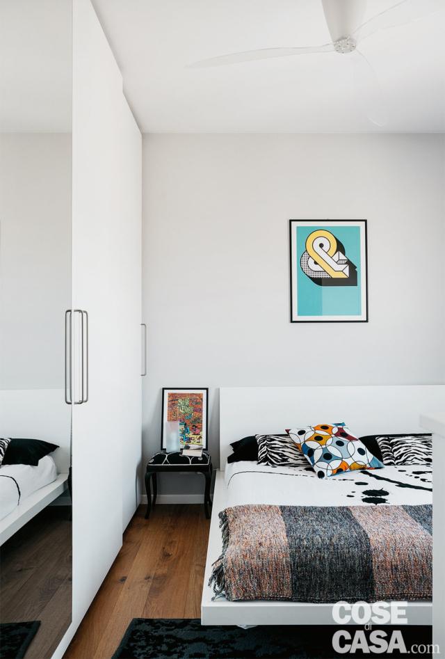 Nella camera matrimoniale, l'armadio a tutta altezza con ante in laccato bianco e specchiate e il letto sono stati su misura. Al centro del soffitto, le pale del ventilatore. Nella camera matrimoniale, l'armadio a tutta altezza con ante in laccato bianco e specchiate e il letto sono stati su misura. Al centro del soffitto, le pale del ventilatore.