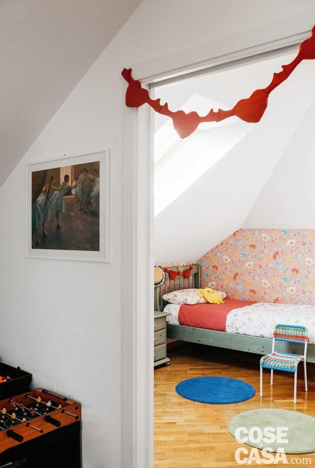 Nella cameretta rosa della bambina, nel sottotetto rinnovato, la tappezzeria definisce e incornicia la parete che fa da sfondo al letto Nella cameretta rosa della bambina, nel sottotetto rinnovato, la tappezzeria definisce e incornicia la parete che fa da sfondo al letto
