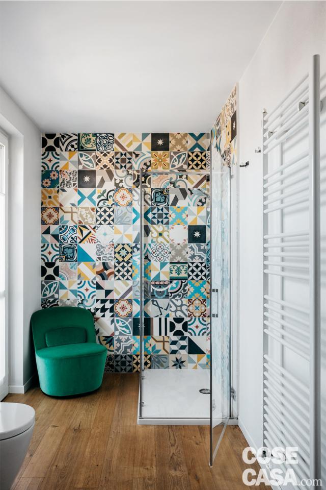 Nel bagno del sottotetto rinnovato i decori policromi delle cementine a parete, la luminosità naturale e dettagli quali la poltroncina "da salotto" nell'angolo. Nel bagno del sottotetto rinnovato i decori policromi delle cementine a parete, la luminosità naturale e dettagli quali la poltroncina "da salotto" nell'angolo.