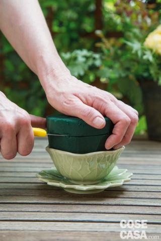 2. Inserire la spugna tagliata nella tazza e abbassarne l’altezza fino a 2 cm sopra il bordo, quindi smussare i lati per avere una maggiore superficie in cui inserire i fiori. 2. Inserire la spugna tagliata nella tazza e abbassarne l’altezza fino a 2 cm sopra il bordo, quindi smussare i lati per avere una maggiore superficie in cui inserire i fiori.