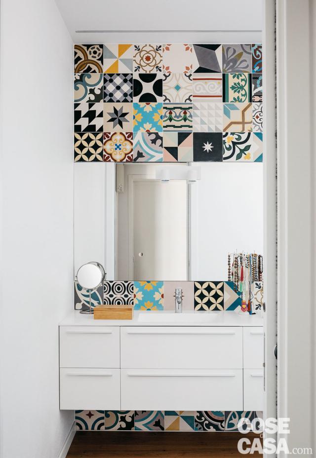 Nella zona lavabo il rivestimento policromo incornicia, sopra e sotto, il volume sospeso del mobile in laccato bianco opaco e la specchiera senza cornice. Nella zona lavabo il rivestimento policromo incornicia, sopra e sotto, il volume sospeso del mobile in laccato bianco opaco e la specchiera senza cornice.