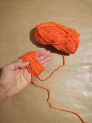 1.Per dare forma alla mini zucca arrotolate il filo di lana arancione sul palmo della mano chiusa, come mostrato in foto, avendo cura di lasciare libero il capo iniziale del filo stesso. Avvolgete per ottenere una matassa piccola e compatta, quindi tagliate la parte finale del filo sfilando con attenzione il lavoro dalla mano. 1.Per dare forma alla mini zucca arrotolate il filo di lana arancione sul palmo della mano chiusa, come mostrato in foto, avendo cura di lasciare libero il capo iniziale del filo stesso. Avvolgete per ottenere una matassa piccola e compatta, quindi tagliate la parte finale del filo sfilando con attenzione il lavoro dalla mano.