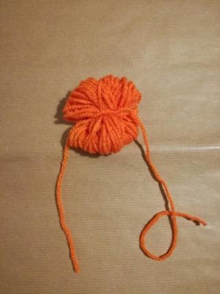 2.Bloccate la matassina ottenuta avvolgendo i due capi del filo sulla parte centrale della stessa, creando una serie di annodature in grado di fermare il tutto senza che la lana si sciolga. Un’annodatura bene tesa potrà fissare il lavoro realizzato gettando le basi per la forma finale del decoro della zucca. 2.Bloccate la matassina ottenuta avvolgendo i due capi del filo sulla parte centrale della stessa, creando una serie di annodature in grado di fermare il tutto senza che la lana si sciolga. Un’annodatura bene tesa potrà fissare il lavoro realizzato gettando le basi per la forma finale del decoro della zucca.