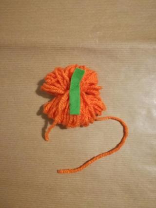 3.Tagliate un segmento piccolo di pannolenci verde, di circa 2,5cm di lunghezza e 1 cm di larghezza, quindi appoggiatelo a cavallo della parte centrale della matassina e fermatelo annodando le due estremità del filo. Incollate le due parti del pannolenci per ottenere un mini picciolo che potrete sagomare con le forbici. 3.Tagliate un segmento piccolo di pannolenci verde, di circa 2,5cm di lunghezza e 1 cm di larghezza, quindi appoggiatelo a cavallo della parte centrale della matassina e fermatelo annodando le due estremità del filo. Incollate le due parti del pannolenci per ottenere un mini picciolo che potrete sagomare con le forbici.