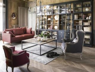 Nel soggiorno arredato da Maisons du Monde, il tavolino da salotto Docks è intarsiato in olmo riciclato e metallo nero. Misura: L 122 x P 122 x H 45 cm. Prezzo: 499,00 euro. L’ambientazione è arredata da due poltrone e un divano. La poltrona Manoir, color grigio talpa, è in lino; misura L 76 x P 80 x H 200 cm; prezzo 499 euro. La poltrona di fianco è la Maupassant in lino color bordeaux; misura L 66 x P 7 x H 80;  prezzo è di 470 euro. Il divano di fronte a 3 posti è il modello Marquis in color terracotta; misura; L 190 x P 95 x H 88 cm; prezzo è di 899 euro. A scaldare l’ambiente è il tappeto grigio Villandry; misura L 140 x  H 200 x P 2 cm; prezzo 249,90 euro. Come sfondo per arredare la parete è stata utilizzata la libreria nera Versailles componibile in più moduli; misure modulo base; di L 101 x P 45 x H 251 cm; prezzo 999 euro. www.maisonsdumonde.com/IT