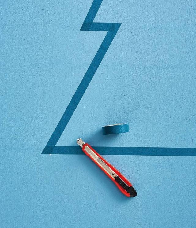 Per definire la sagoma dell’albero, sulla prima linea orizzontale sopra la base, segnare 2 punti all'interno della linea verticale perimetrale a 5 e a 10 cm. Sulla seconda linea orizzontale segnare i 2 punti a 10 e 15 cm. Infine, sulla terza a 15 e 20 cm. Ripetere l'operazione sull'altro lato verticale. Con l'aiuto del righello, a matita, unire tutti i punti su entrambi i lati, per definire il profilo dell'albero. Partendo dal vertice, fissare il washi tape lungo le linee diagonali, poi fissare il nastro sulle linee orizzontali, sagomando gli angoli con il cutter. Per definire la sagoma dell’albero, sulla prima linea orizzontale sopra la base, segnare 2 punti all'interno della linea verticale perimetrale a 5 e a 10 cm. Sulla seconda linea orizzontale segnare i 2 punti a 10 e 15 cm. Infine, sulla terza a 15 e 20 cm. Ripetere l'operazione sull'altro lato verticale. Con l'aiuto del righello, a matita, unire tutti i punti su entrambi i lati, per definire il profilo dell'albero. Partendo dal vertice, fissare il washi tape lungo le linee diagonali, poi fissare il nastro sulle linee orizzontali, sagomando gli angoli con il cutter.