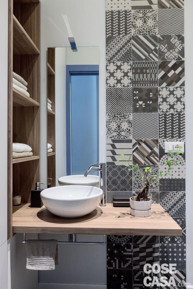 bagno con finiture decorative in gres con decori geometrici in chiaroscuro, lavabo da appoggio a catino, piano e nicchia in rovere, specchio bagno con finiture decorative in gres con decori geometrici in chiaroscuro, lavabo da appoggio a catino, piano e nicchia in rovere, specchio
