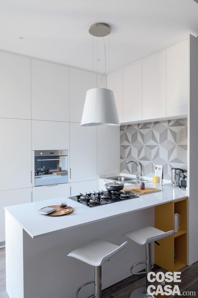 penisola della cucina in laccato bianco con bancone snack e sgabelli da bar, zona cottura con piano a gas in acciaio inox e cappa d'arredo penisola della cucina in laccato bianco con bancone snack e sgabelli da bar, zona cottura con piano a gas in acciaio inox e cappa d'arredo