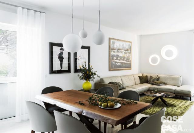 open space del living, zona conversazione, divano angolare in pelle, tavolo in legno, sedie, lampade a sospensione sferiche, portafinestra open space del living, zona conversazione, divano angolare in pelle, tavolo in legno, sedie, lampade a sospensione sferiche, portafinestra