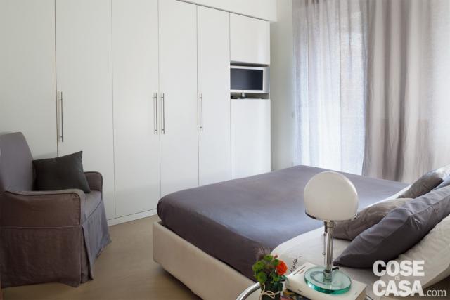 camera matrimoniale, armadio a tutta parete in laccato bianco, zona tv integrata, letto tessile, poltrona, tendaggi camera matrimoniale, armadio a tutta parete in laccato bianco, zona tv integrata, letto tessile, poltrona, tendaggi
