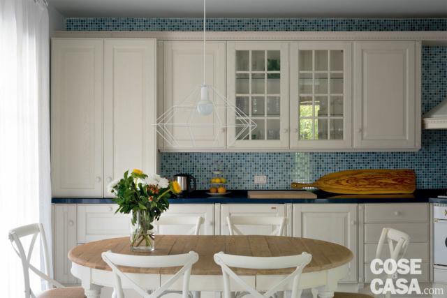 cucina tradizionale, rivestimento a mosaico, pensili vetrati, tavolo da pranzo con piano in legno, sedie bianche cucina tradizionale, rivestimento a mosaico, pensili vetrati, tavolo da pranzo con piano in legno, sedie bianche
