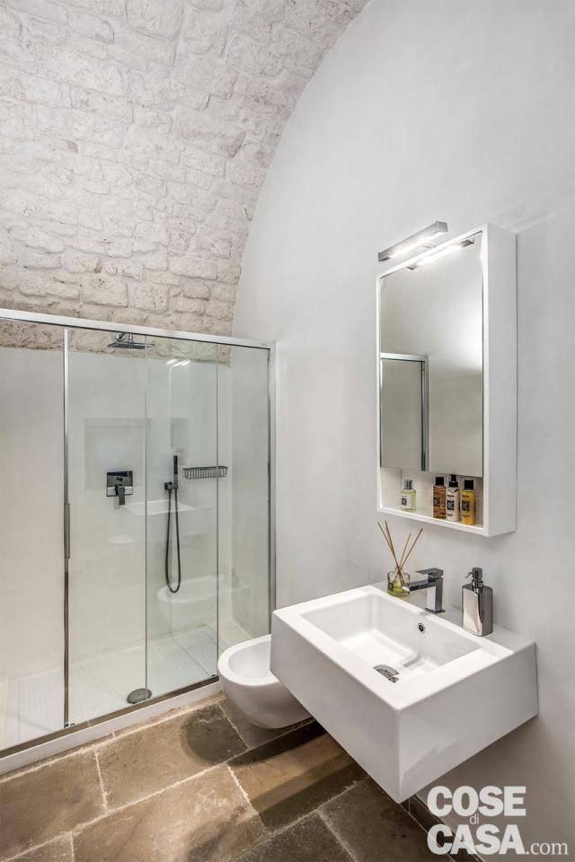 Il bagno a servizio della camera matrimoniale è stato ricavato sfruttando l’ampia metratura dell’ambiente e la presenza al suo fianco di una alcova tradizionale, ora utilizzata come cabina armadio. La pavimentazione pertanto è la stessa a chianche, su cui spiccano i sanitari bianchi di Ceramica Flaminia (accessoriati con rubinetteria Mariani) e il box doccia Duka, di segno assolutamente contemporaneo. Lo specchio contenitore dalla linea essenziale, anch’esso declinato in bianco, è invece di Pozzi Ginori. Per evitare di piastrellare, le pareti sono rivestite con micro-cemento resinato Stone International, che ne preserva la resistenza all’acqua e all’umidità. Il bagno a servizio della camera matrimoniale è stato ricavato sfruttando l’ampia metratura dell’ambiente e la presenza al suo fianco di una alcova tradizionale, ora utilizzata come cabina armadio. La pavimentazione pertanto è la stessa a chianche, su cui spiccano i sanitari bianchi di Ceramica Flaminia (accessoriati con rubinetteria Mariani) e il box doccia Duka, di segno assolutamente contemporaneo. Lo specchio contenitore dalla linea essenziale, anch’esso declinato in bianco, è invece di Pozzi Ginori. Per evitare di piastrellare, le pareti sono rivestite con micro-cemento resinato Stone International, che ne preserva la resistenza all’acqua e all’umidità.