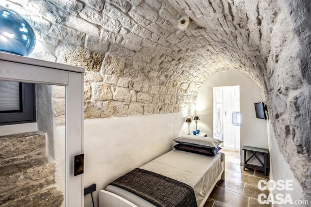 In uno dei due magazzini preesistenti sulla copertura terrazzata della palazzina è stata ricavata la seconda camera da letto, singola, dotata di bagno privato. Anche qui per dare unitarietà all’insieme, si è scelto di posare a pavimento chianche di pietra Bronzetto di Trani, mentre la volta a botte di pietra Roccato di Ostuni lasciata a vista richiama i caratteri architettonici del piano sottostante. Date le dimensioni esigue dell’ambiente, tutti i mobili (di Scandola) sono stati realizzati su misura, mentre il piccolo bagno ospita solamente doccia, wc e lavabo (sanitari Ceramica Flaminia). In uno dei due magazzini preesistenti sulla copertura terrazzata della palazzina è stata ricavata la seconda camera da letto, singola, dotata di bagno privato. Anche qui per dare unitarietà all’insieme, si è scelto di posare a pavimento chianche di pietra Bronzetto di Trani, mentre la volta a botte di pietra Roccato di Ostuni lasciata a vista richiama i caratteri architettonici del piano sottostante. Date le dimensioni esigue dell’ambiente, tutti i mobili (di Scandola) sono stati realizzati su misura, mentre il piccolo bagno ospita solamente doccia, wc e lavabo (sanitari Ceramica Flaminia).