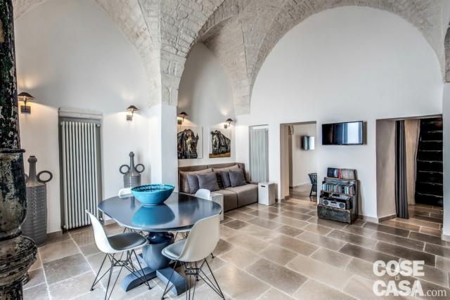 L’ambiente principale della casa si distingue per le alte volte di pietra Roccato di Ostuni lasciate a vista e per la pavimentazione tipica di chianche di pietra Bronzetto di Trani, posate direttamente sul gres porcellanato preesistente (soluzione che riduce sensibilmente sia i tempi di cantiere sia i costi). Pochi gli arredi, scelti in tonalità neutre a parte qualche tocco di blu, come ad esempio la laccatura del tavolo in stile (di Marchetti Maison), accostato a sedie di design (Eames Plastic Side Chair di Vitra). L’illuminazione è risolta con apparecchi a parete Ambra di Anna Lari, di segno rétro. I radiatori Tesi di Irsap sono posizionati in nicchia per ridurne l’ingombro. L’ambiente principale della casa si distingue per le alte volte di pietra Roccato di Ostuni lasciate a vista e per la pavimentazione tipica di chianche di pietra Bronzetto di Trani, posate direttamente sul gres porcellanato preesistente (soluzione che riduce sensibilmente sia i tempi di cantiere sia i costi). Pochi gli arredi, scelti in tonalità neutre a parte qualche tocco di blu, come ad esempio la laccatura del tavolo in stile (di Marchetti Maison), accostato a sedie di design (Eames Plastic Side Chair di Vitra). L’illuminazione è risolta con apparecchi a parete Ambra di Anna Lari, di segno rétro. I radiatori Tesi di Irsap sono posizionati in nicchia per ridurne l’ingombro.