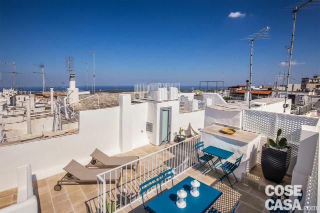 La copertura terrazzata della palazzina storica, con spettacolare vista sui tetti e sul mare di Ostuni, è stata riprogettata per creare una serie di spazi a diverse altezze, in grado di diversificare funzioni e livello di privacy desiderato. Il lastrico solare è stato pertanto messo in sicurezza e protetto con apposite ringhiere e parapetti. Le due diverse altane sulle coperture della camera singola e della cucina ospitano così una zona pranzo, con tavolo e sedie di metallo della linea Arc en Ciel di Emu, e un angolo relax con imbottiti outdoor di Gervasoni. La copertura terrazzata della palazzina storica, con spettacolare vista sui tetti e sul mare di Ostuni, è stata riprogettata per creare una serie di spazi a diverse altezze, in grado di diversificare funzioni e livello di privacy desiderato. Il lastrico solare è stato pertanto messo in sicurezza e protetto con apposite ringhiere e parapetti. Le due diverse altane sulle coperture della camera singola e della cucina ospitano così una zona pranzo, con tavolo e sedie di metallo della linea Arc en Ciel di Emu, e un angolo relax con imbottiti outdoor di Gervasoni.