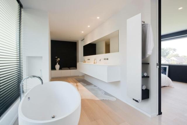 Bagno con radiatore bianco Niva Bath di Vasco attrezzato lungo la parete con ripiani e appendino Bagno con radiatore bianco Niva Bath di Vasco attrezzato lungo la parete con ripiani e appendino