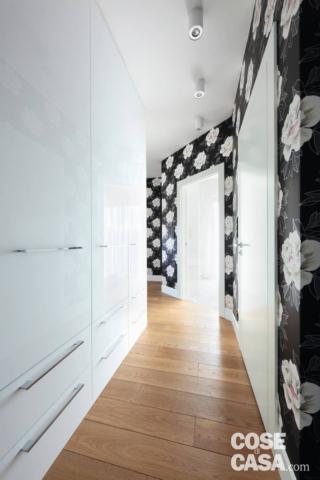 A crocked hallway with shiny, built-in cupboards and black and white floral wallpaper