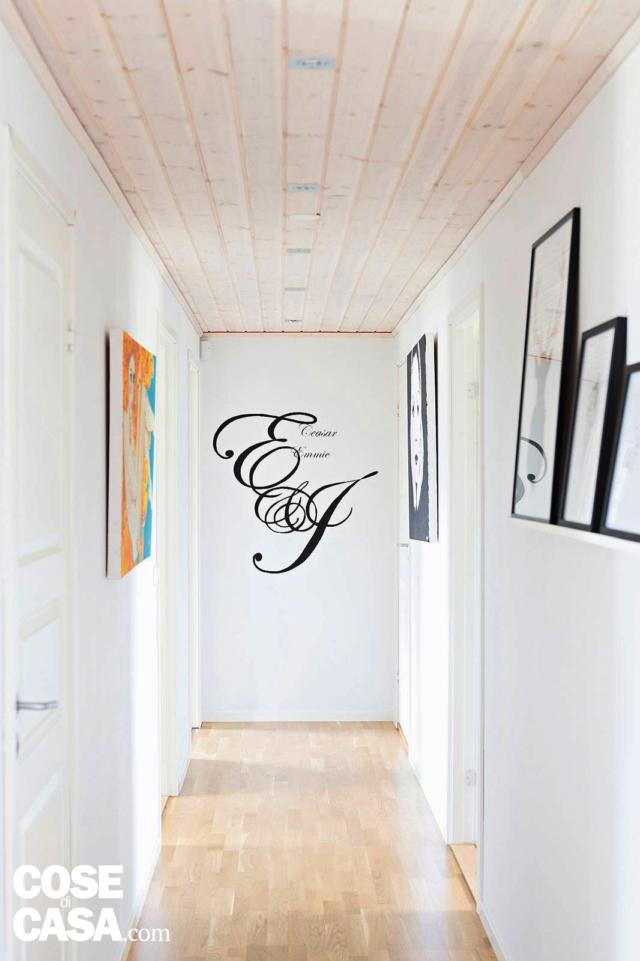 corridoio con quadri a parete, pavimento e soffitto rivestiti in legno e pareti bianche corridoio con quadri a parete, pavimento e soffitto rivestiti in legno e pareti bianche