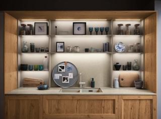 La cucina si sviluppa su due pareti parallele collegate da un’isola rivestita
in Caranto Quartz e completata
da sgabelli Trinity neri. La funzione “dispensa” è assolta dalle colonne,
dalle cassettiere e dallo schienale Stepsystem Reverse (foto a sinistra). Questo, incorniciato da pannelli
in Rovere Nodoso Chiaro,
è attrezzato con schienali
in Caranto Quartz Auriga e ripiani
in alluminio con barre a led per l'illuminazione naturale. La gola Shellsystem delle colonne si coordina alle ante e allo zoccolo in finitura Titanio, che conferiscono all'ambiente un look raffinato ed elegante.