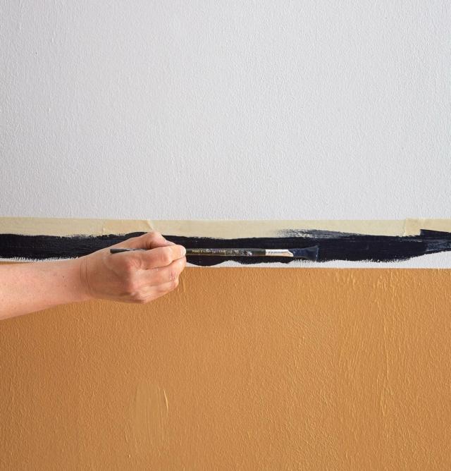Applicare il nastro di carta adesiva a protezione della linea superiore della fascia centrale, in modo da non sbavare con il colore sulla parete che sarà stata dipinta di bianco (seguire le indicazioni al n. 4). Con attenzione stendere la tinta Black lungo la fascia centrale senza creare sbavature. Ripetere se necessario per un decoro uniforme e lasciare asciugare. Eliminare il nastro di carta e correggere eventuali imperfezioni. Applicare il nastro di carta adesiva a protezione della linea superiore della fascia centrale, in modo da non sbavare con il colore sulla parete che sarà stata dipinta di bianco (seguire le indicazioni al n. 4). Con attenzione stendere la tinta Black lungo la fascia centrale senza creare sbavature. Ripetere se necessario per un decoro uniforme e lasciare asciugare. Eliminare il nastro di carta e correggere eventuali imperfezioni.
