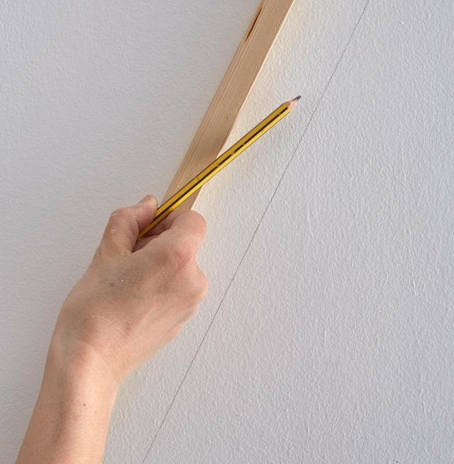tirare riga su parete bianca per dipingere fascia geometrica di diverso colore tirare riga su parete bianca per dipingere fascia geometrica di diverso colore