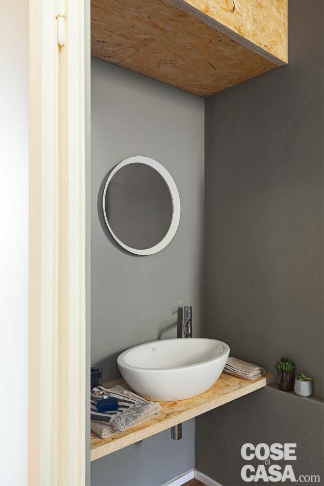 bagno dell'abitazione da single, piano sospeso, lavabo a catino, specchio tondo, parete grigia bagno dell'abitazione da single, piano sospeso, lavabo a catino, specchio tondo, parete grigia