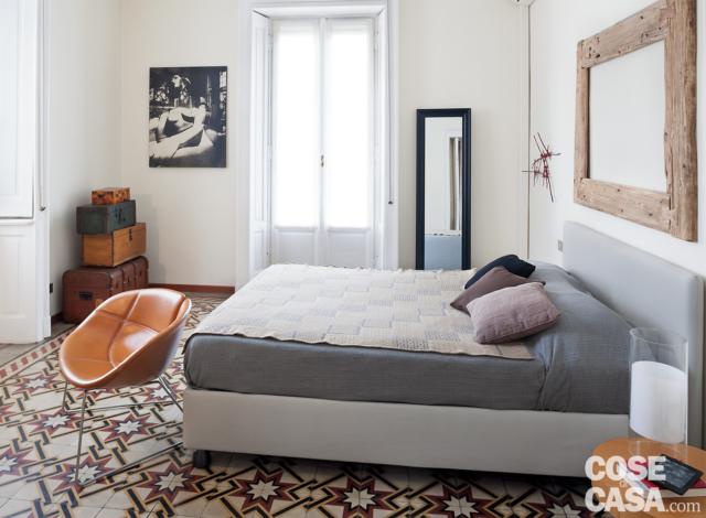 bilocale 75 mq, camera matrimoniale, finestre su due lati, letto tessile con testiera, specchio appeso con cornice in legno, specchio appoggiato a parete, poltroncina rivestita in cuoio, pavimento in cementine decorate bilocale 75 mq, camera matrimoniale, finestre su due lati, letto tessile con testiera, specchio appeso con cornice in legno, specchio appoggiato a parete, poltroncina rivestita in cuoio, pavimento in cementine decorate